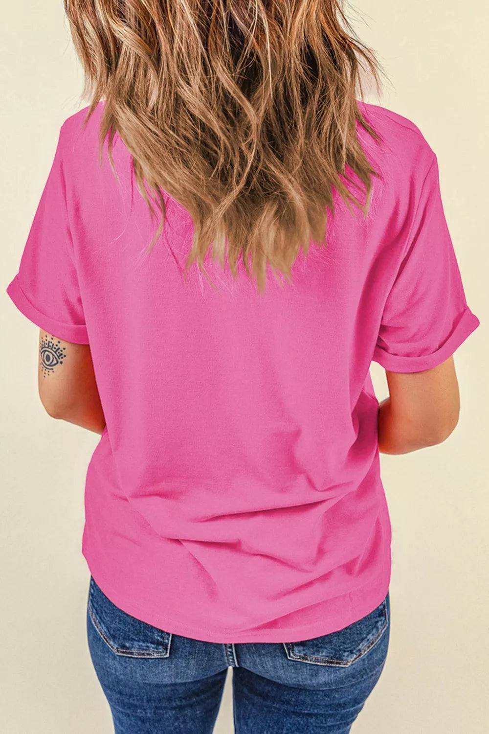 Bright pink short sleeve graphic tee with a colorful floral starfish design on the front, styled with light wash denim jeans.