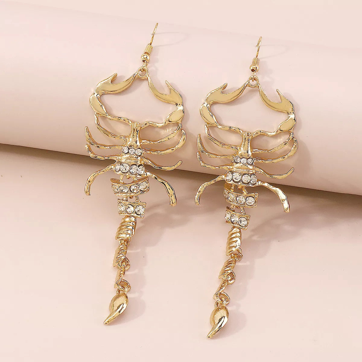 Gold scorpion-shaped rhinestone statement earrings with ribbed detailing.