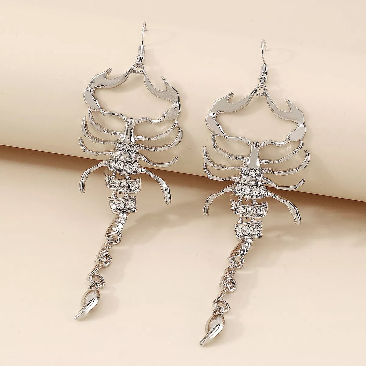 Silver scorpion-shaped rhinestone statement earrings with ribbed detailing.