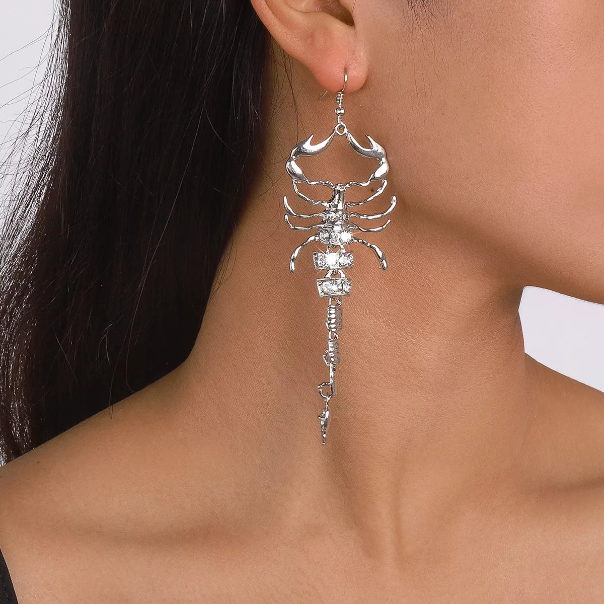 Silver scorpion-shaped rhinestone statement earrings with ribbed detailing.