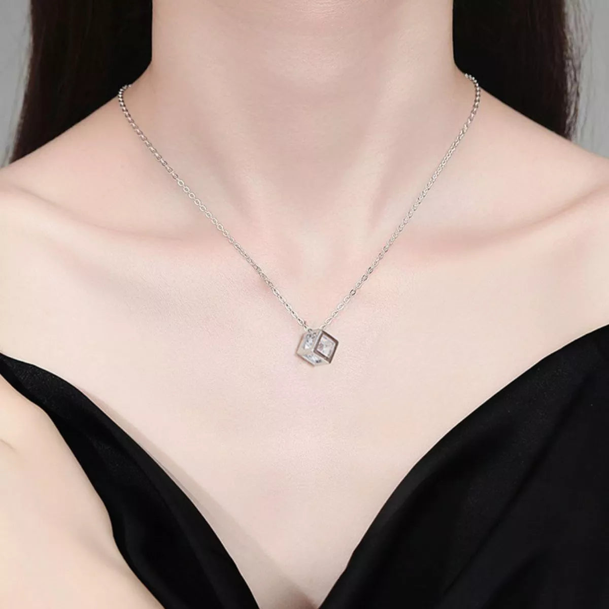 Platinum plated sterling silver geometric pendant necklace featuring a sparkling moissanite stone on a dark textured background