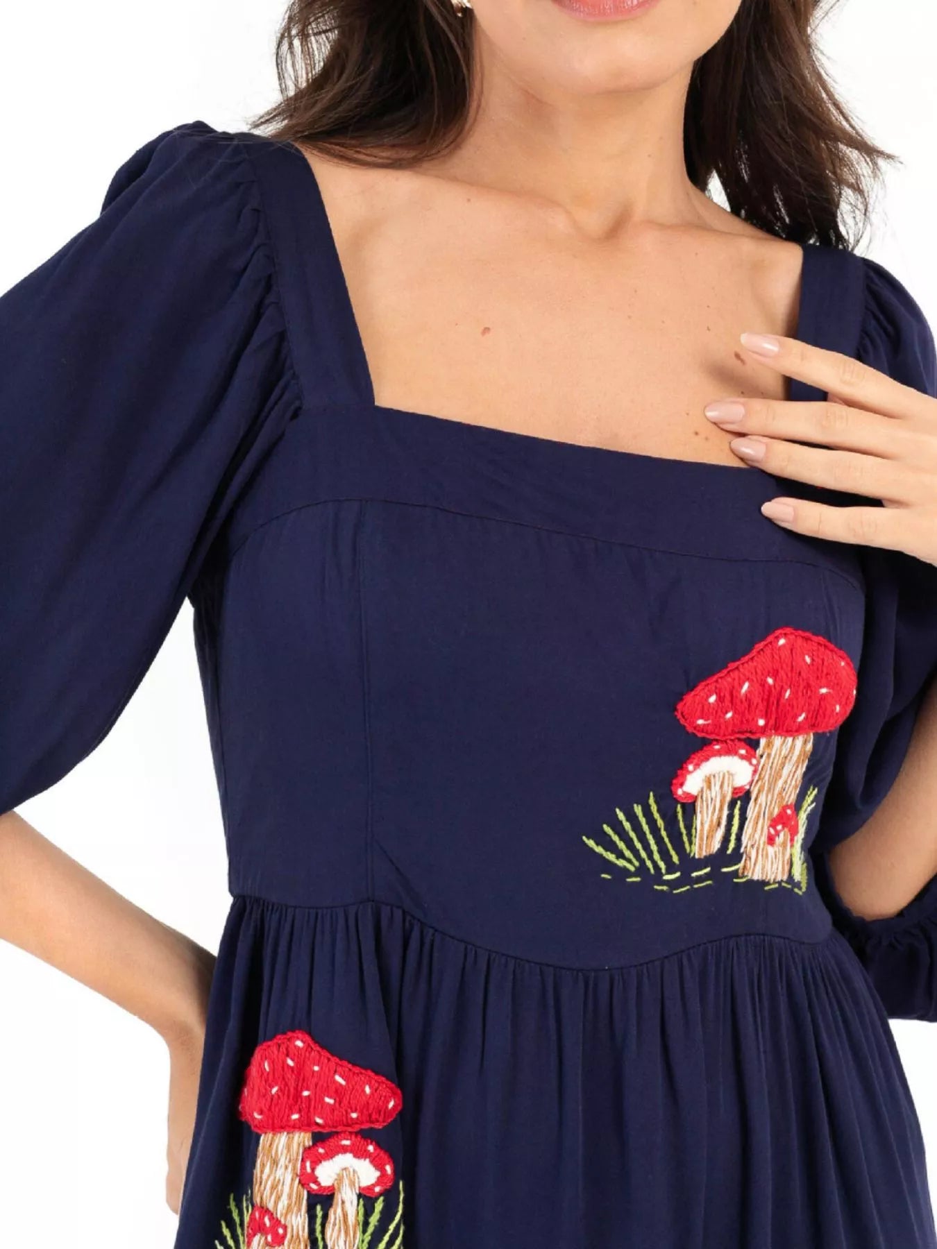 Woman wearing navy maxi dress with red mushroom embroidery and square neckline