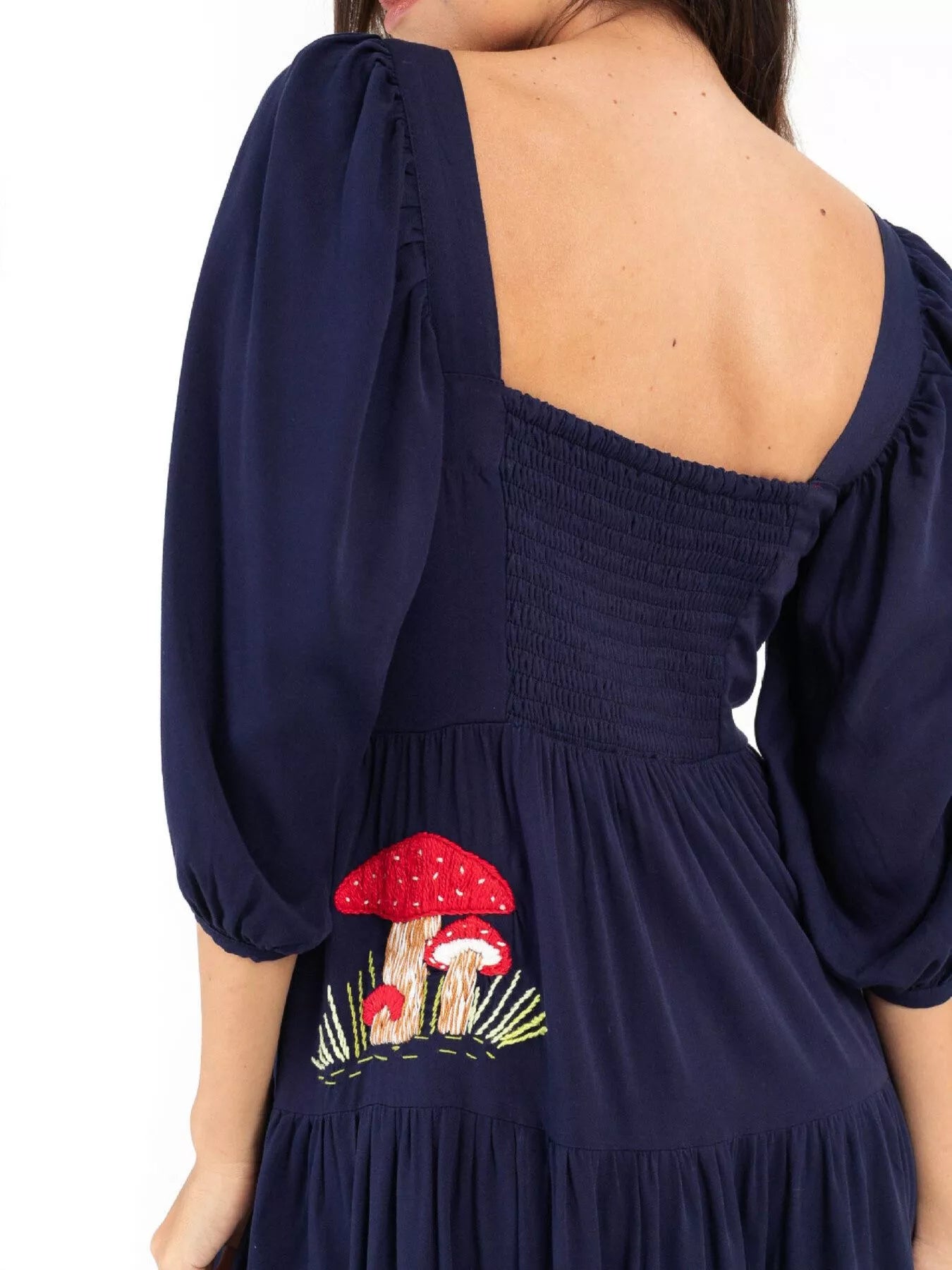 Woman wearing navy maxi dress with red mushroom embroidery and square neckline
