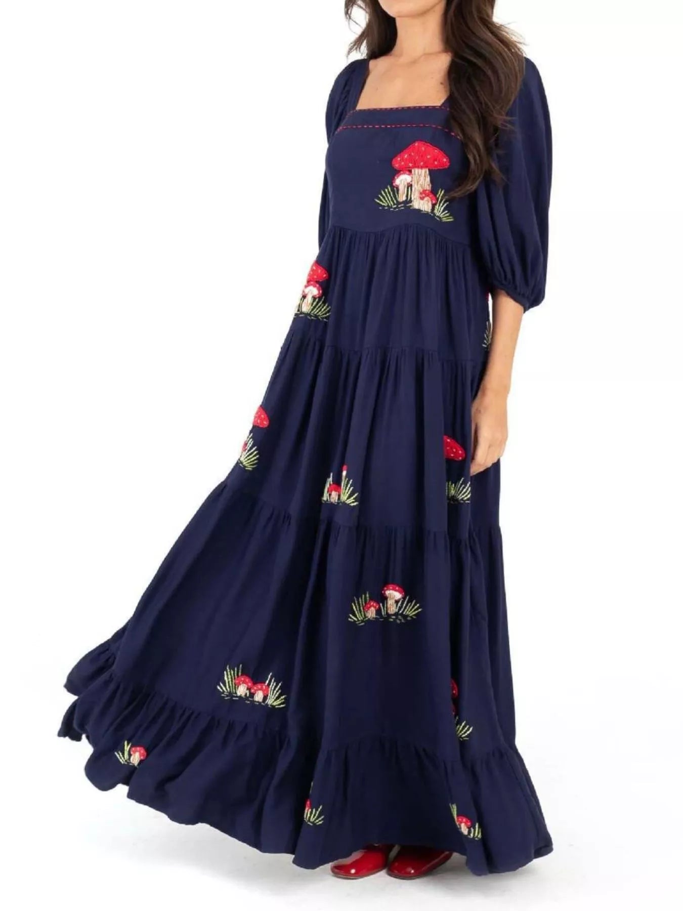 Woman wearing navy maxi dress with red mushroom embroidery and square neckline