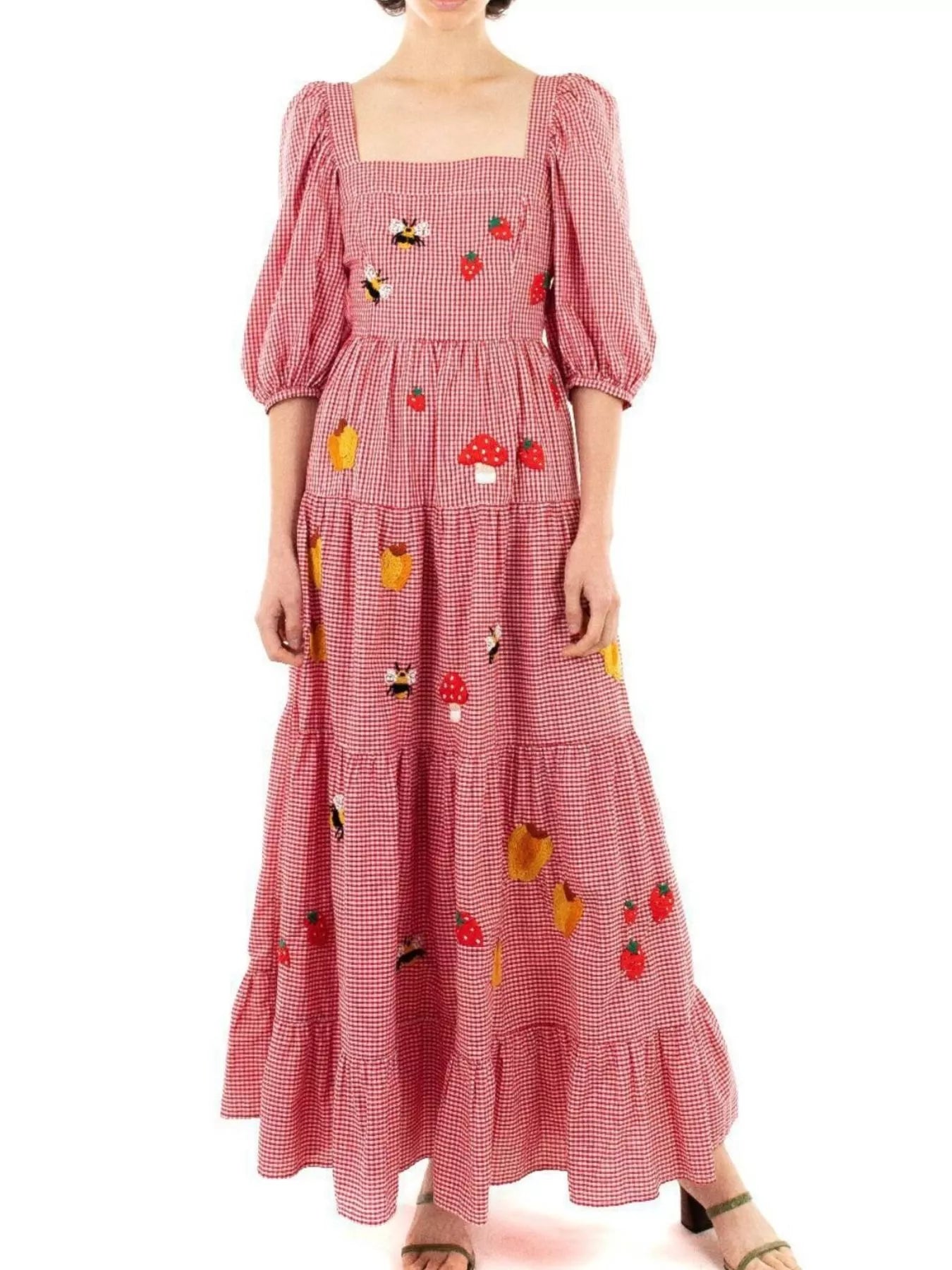Woman in red gingham maxi dress with embroidered strawberries, bees, and mushrooms