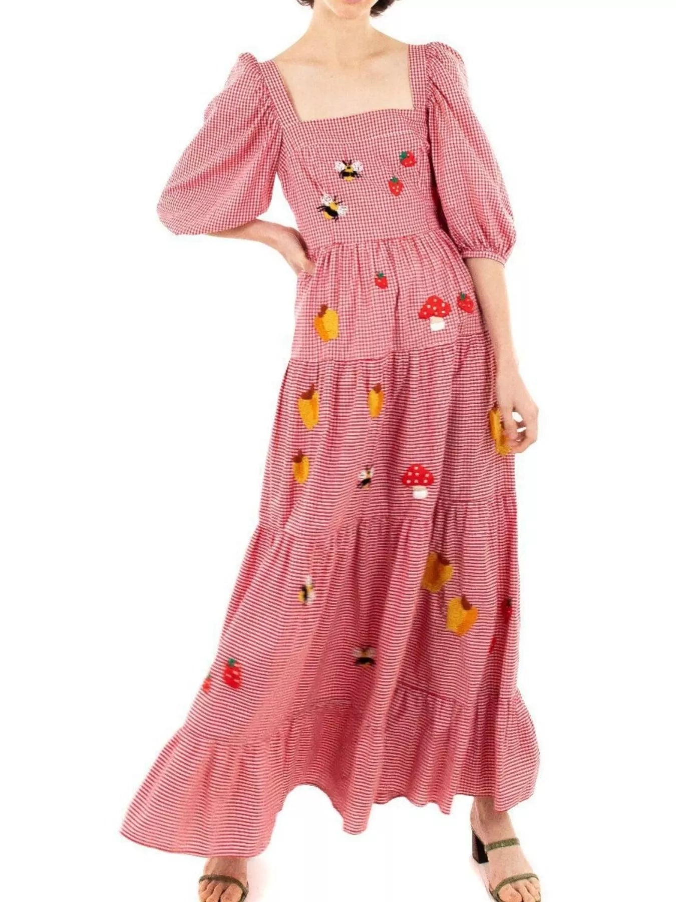 Woman in red gingham maxi dress with embroidered strawberries, bees, and mushrooms