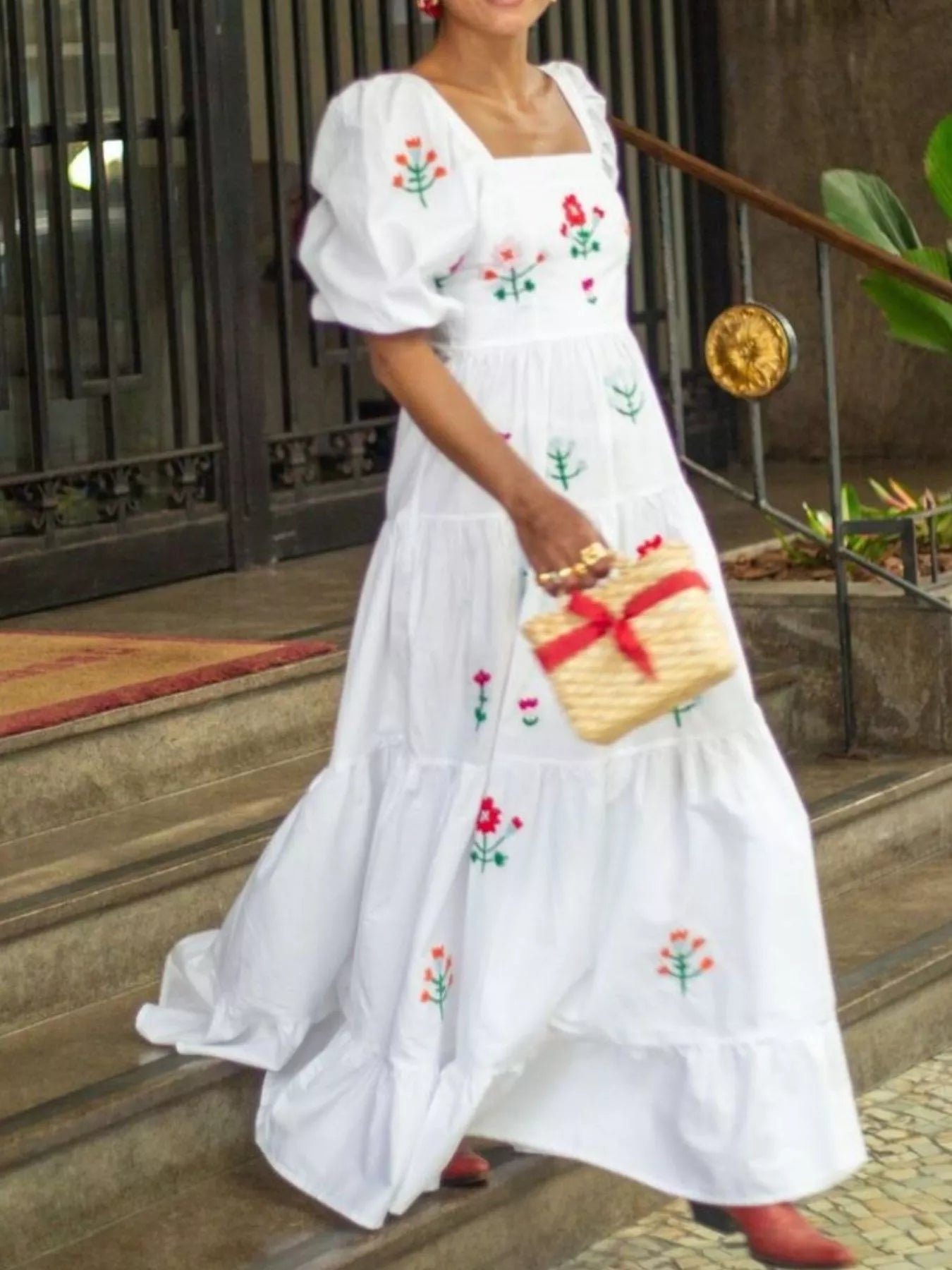 White maxi dress with colorful floral embroidery, square neckline, and ruffled tiers