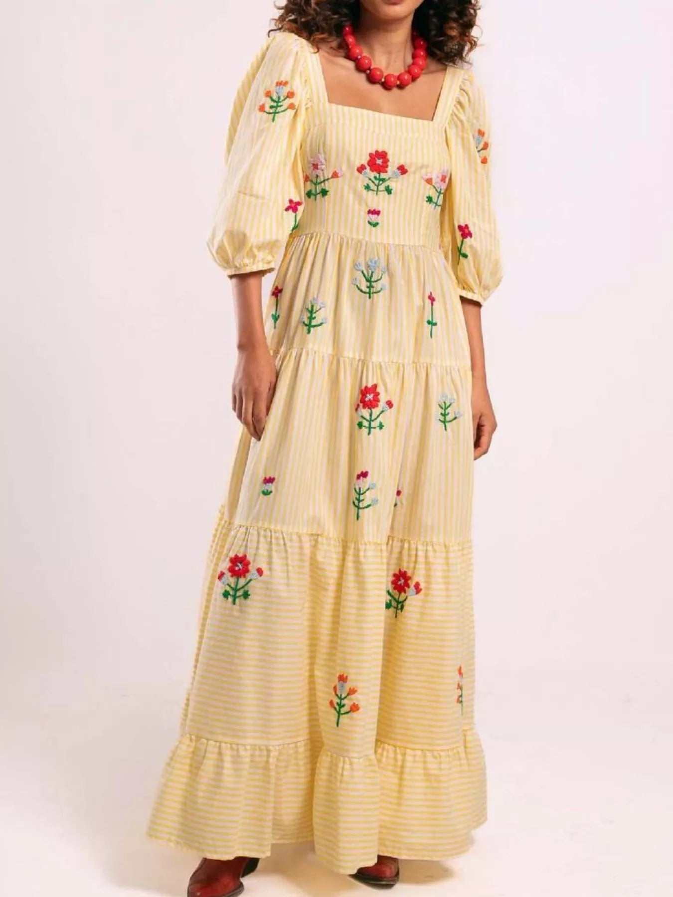 Woman wearing yellow striped maxi dress with colorful floral embroidery and puff sleeves