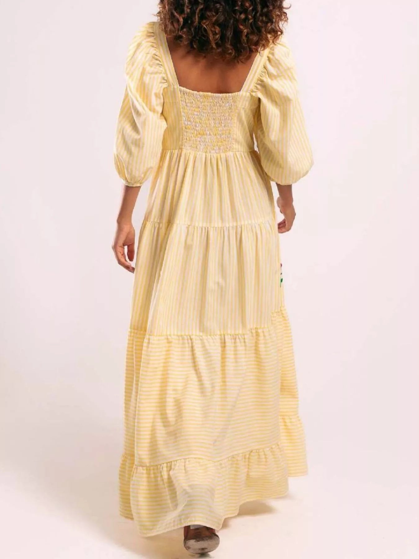 Woman wearing yellow striped maxi dress with colorful floral embroidery and puff sleeves