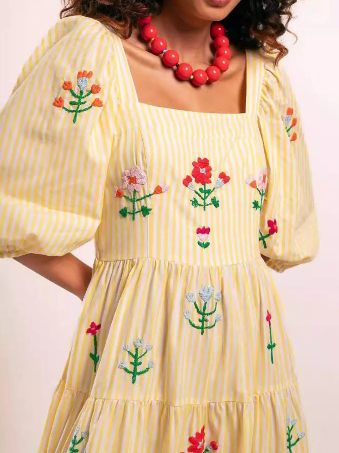 Woman wearing yellow striped maxi dress with colorful floral embroidery and puff sleeves