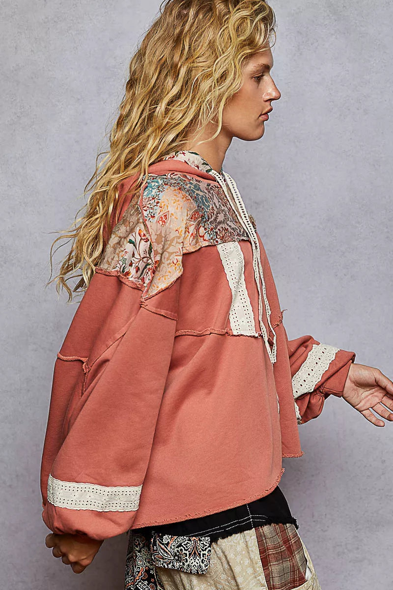 Woman wearing a relaxed-fit patchwork balloon sleeve hoodie with embroidered details and drawstring hood