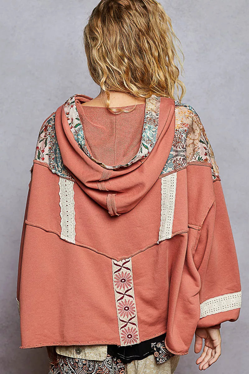 Woman wearing a relaxed-fit patchwork balloon sleeve hoodie with embroidered details and drawstring hood