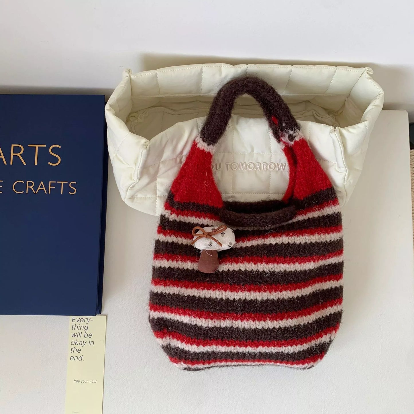 Small striped knit tote bag with mushroom charm detail and textured handle.