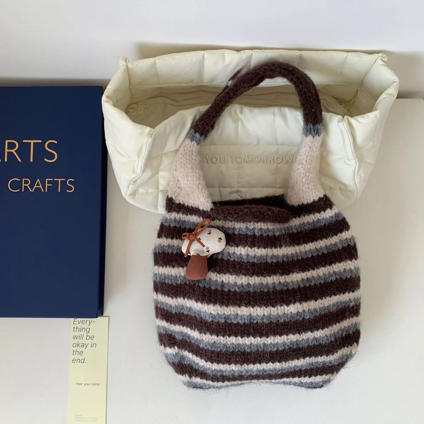 Small striped knit tote bag with mushroom charm detail and textured handle.
