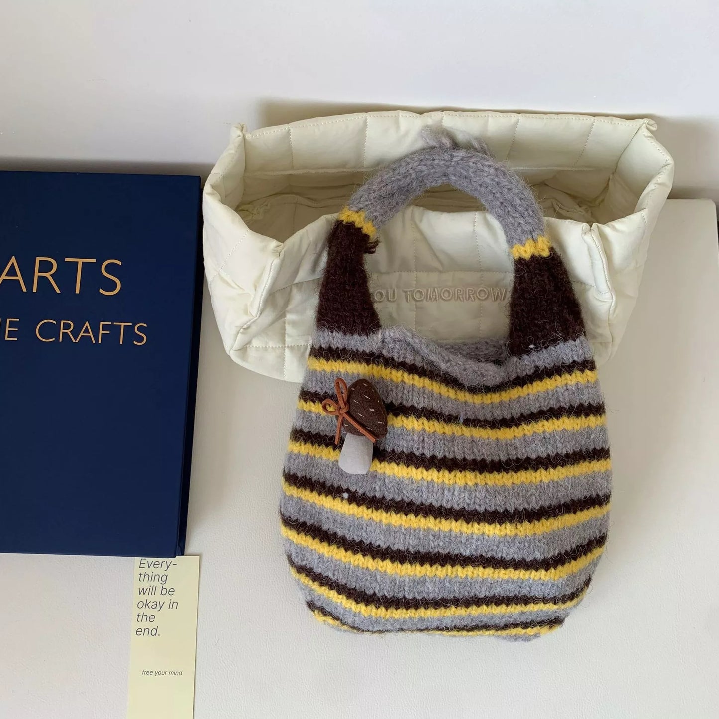 Small striped knit tote bag with mushroom charm detail and textured handle.