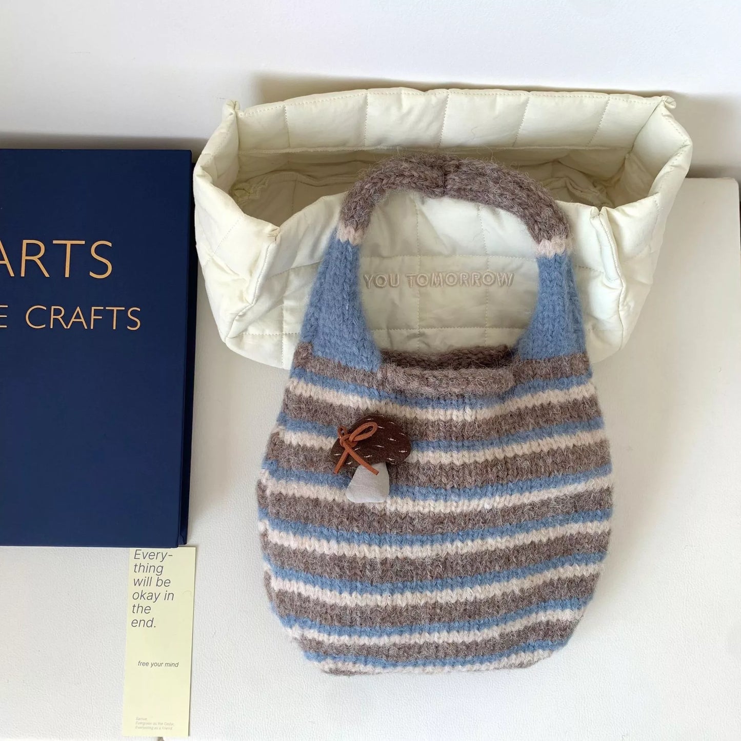 Small striped knit tote bag with mushroom charm detail and textured handle.