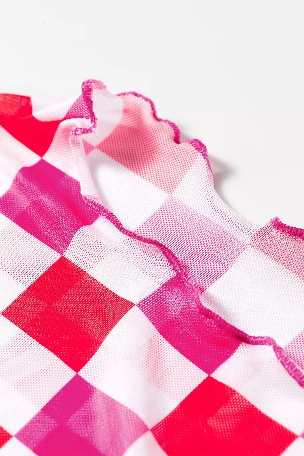Bright pink and red checkered sheer mesh long sleeve top with a slightly stretchy fit styled with light denim jeans.