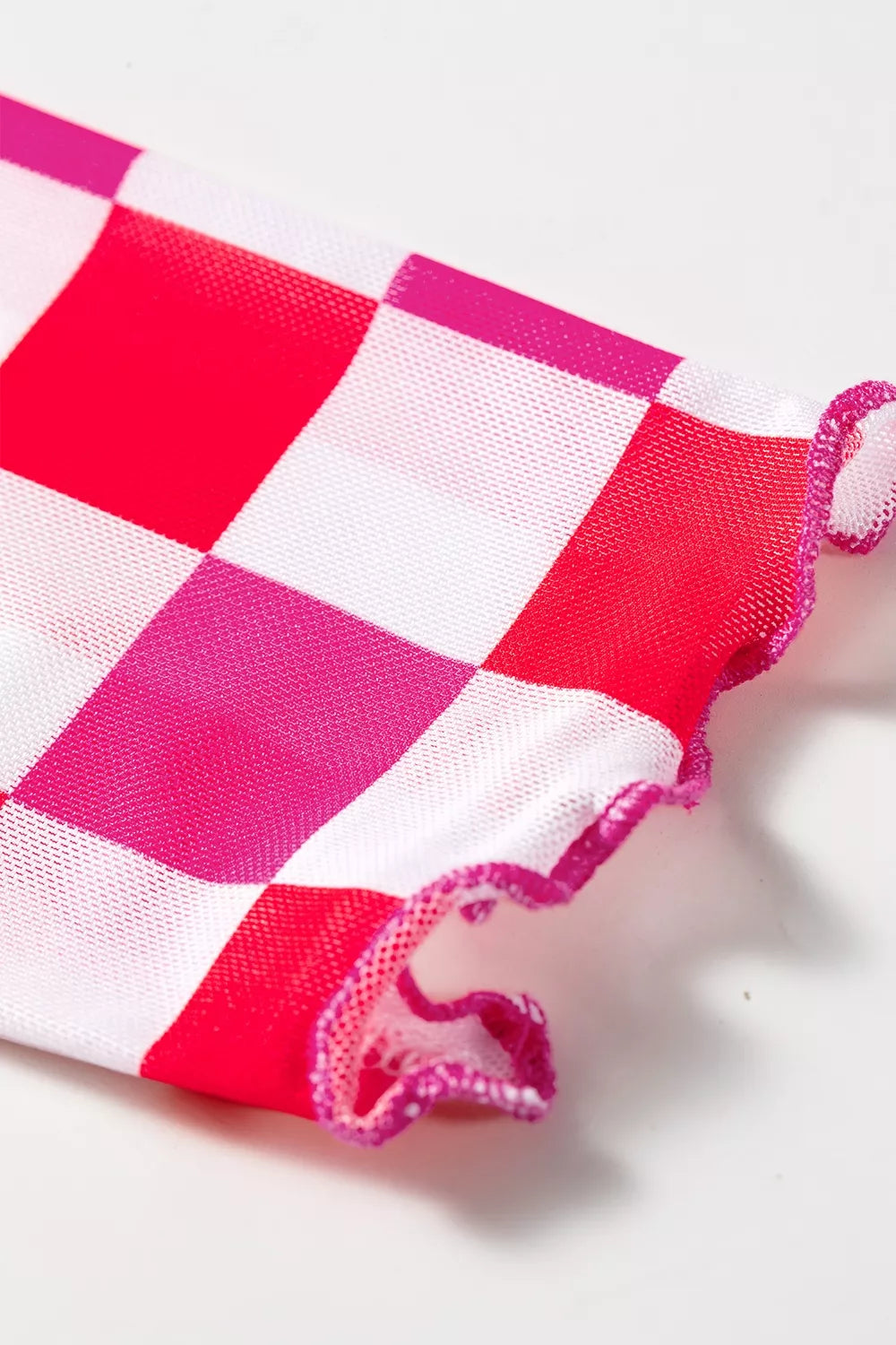 Bright pink and red checkered sheer mesh long sleeve top with a slightly stretchy fit styled with light denim jeans.