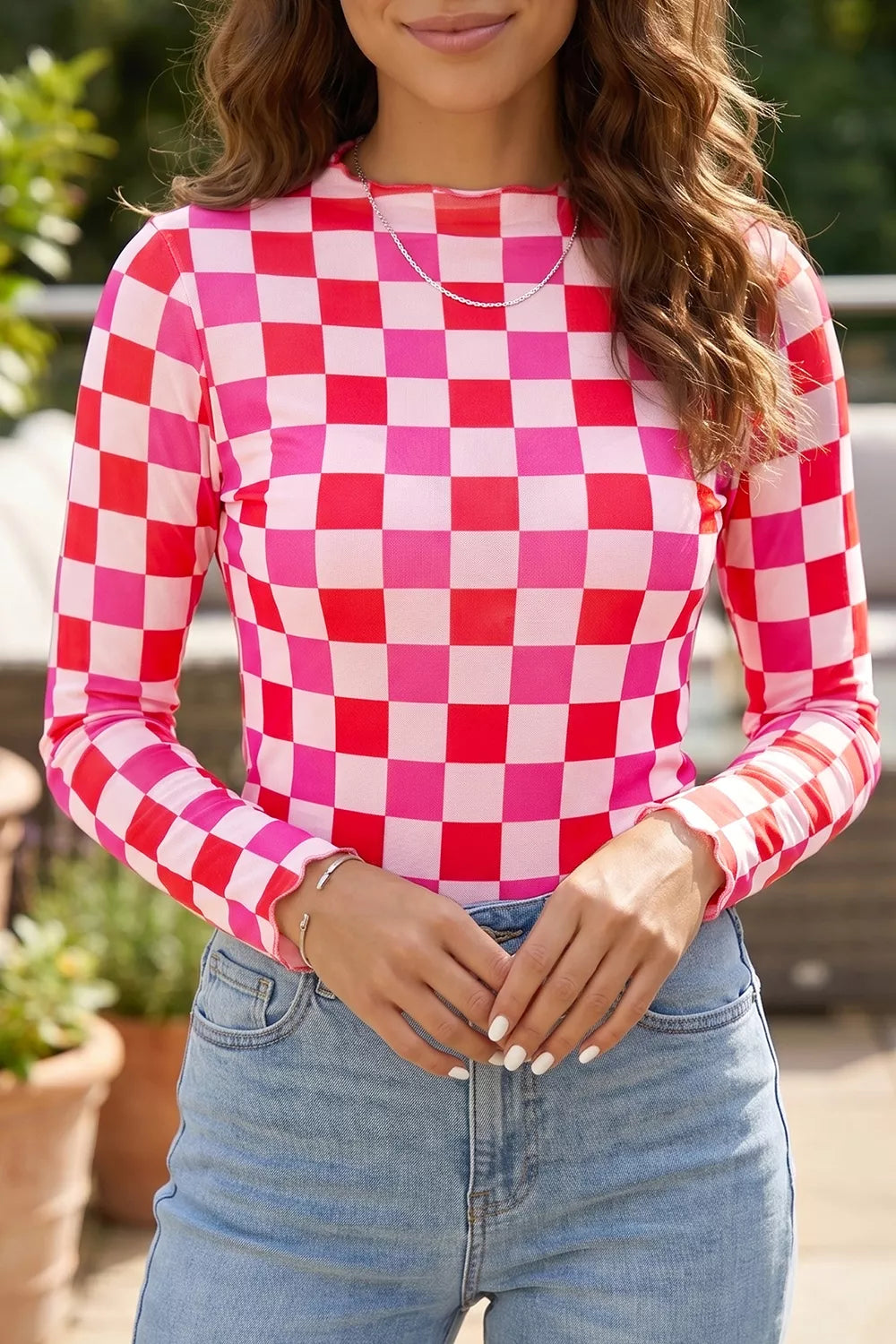 Bright pink and red checkered sheer mesh long sleeve top with a slightly stretchy fit styled with light denim jeans.