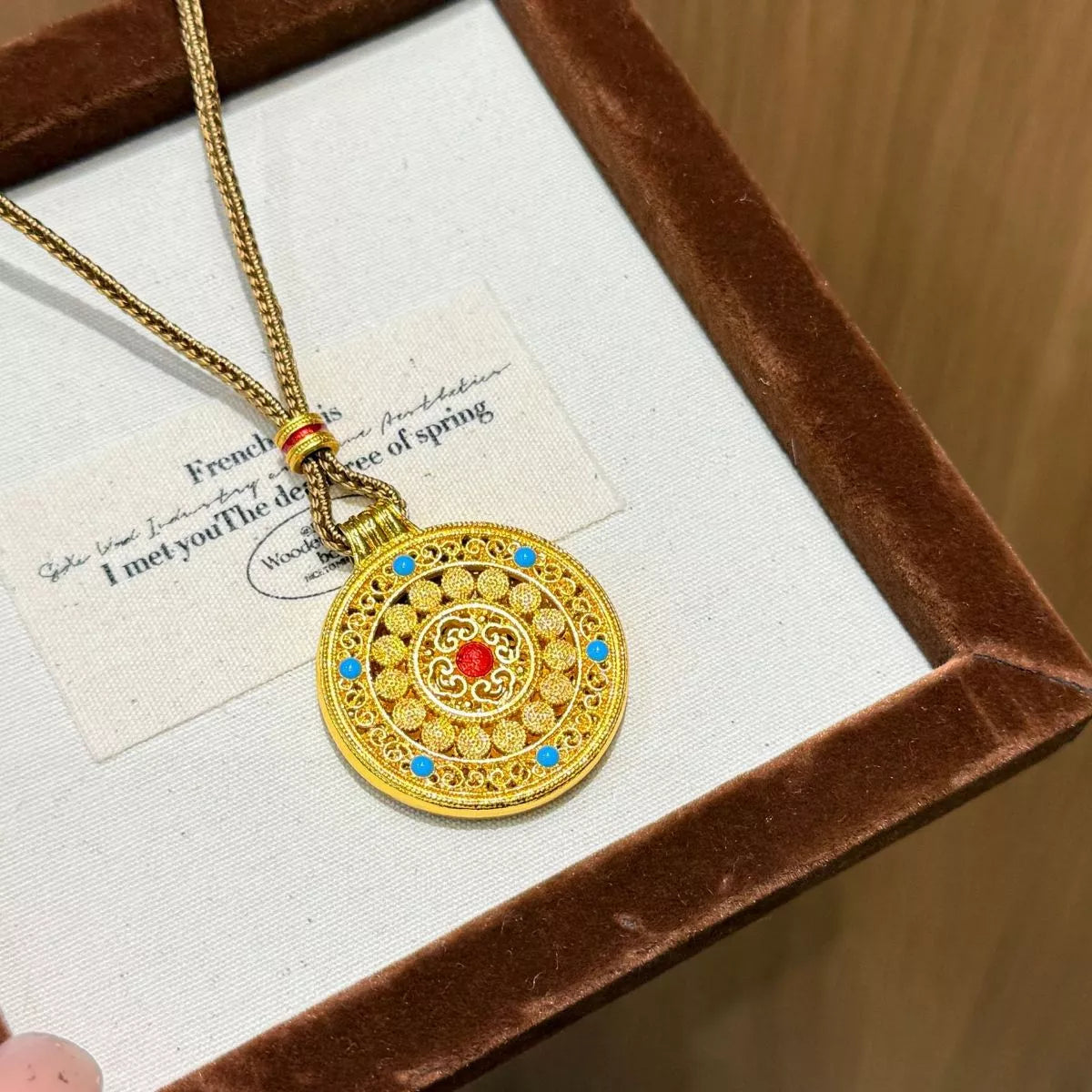18K gold-plated medallion necklace with ornate circular design, zircon accents, and colorful red and turquoise details.