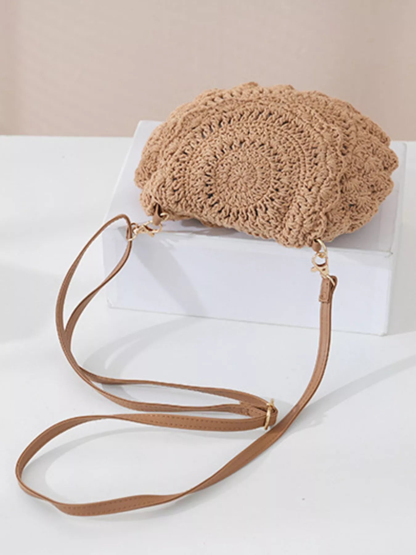 Small round crochet crossbody bag in natural beige cotton thread with scalloped edges and a flap closure.