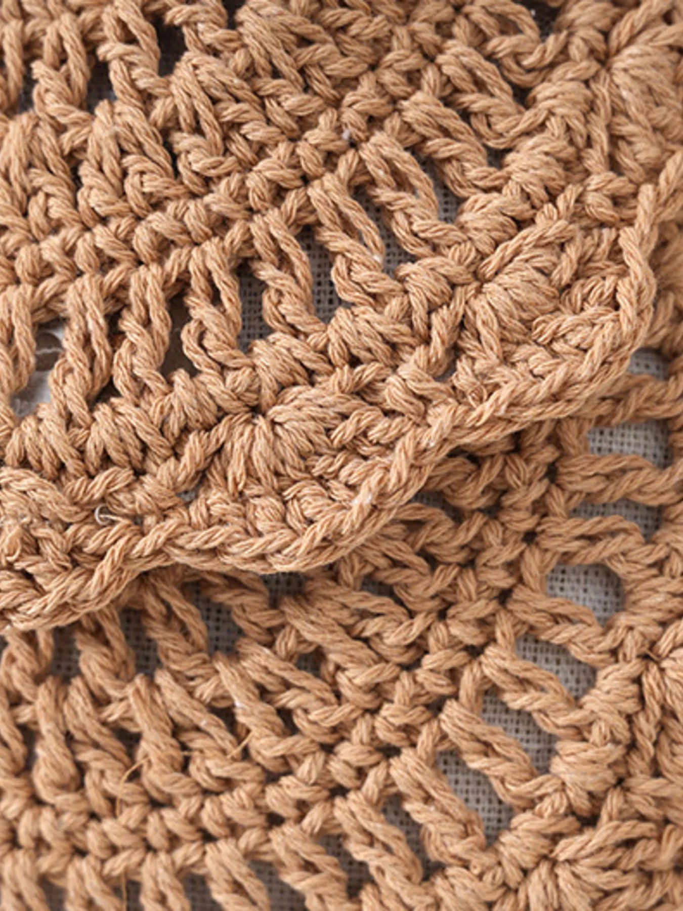 Small round crochet crossbody bag in natural beige cotton thread with scalloped edges and a flap closure.