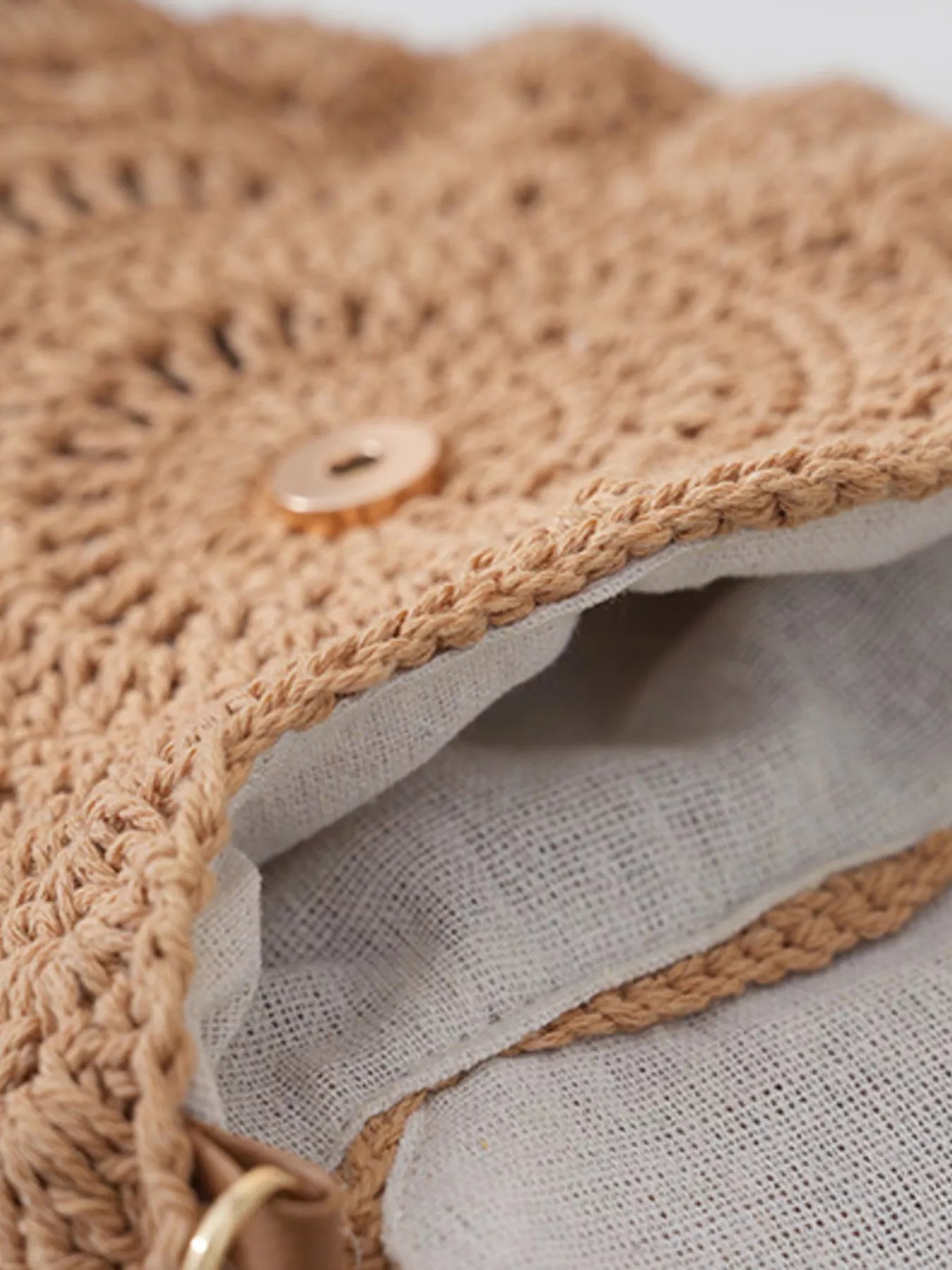 Small round crochet crossbody bag in natural beige cotton thread with scalloped edges and a flap closure.