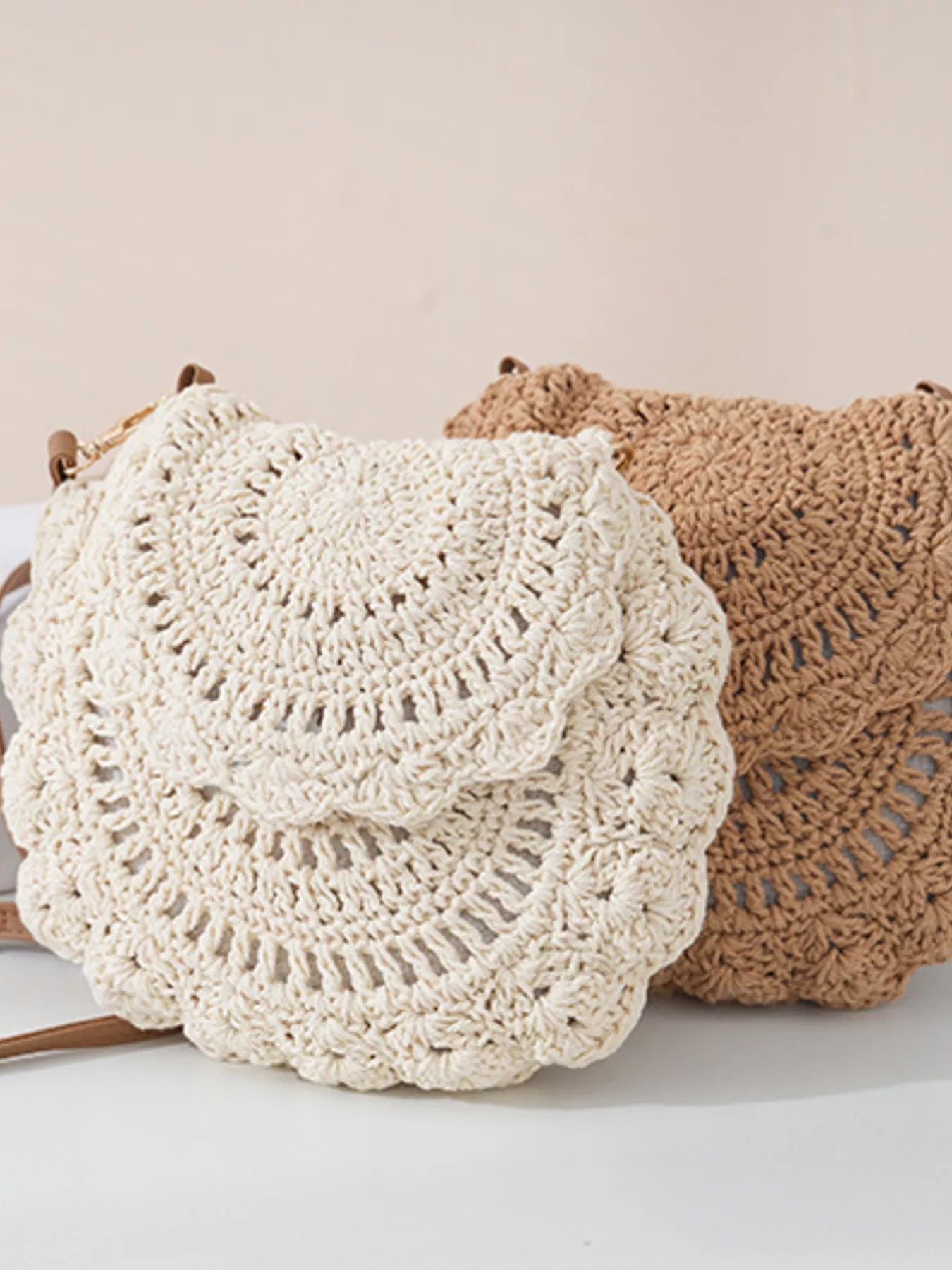 Small round crochet crossbody bag in natural beige and white cotton thread with scalloped edges and a flap closure.