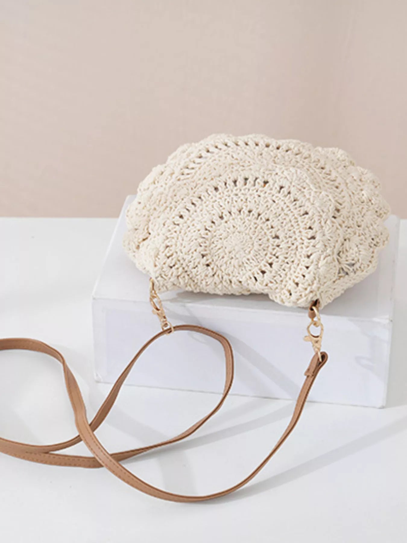 Small round crochet crossbody bag in white cotton thread with scalloped edges and a flap closure.