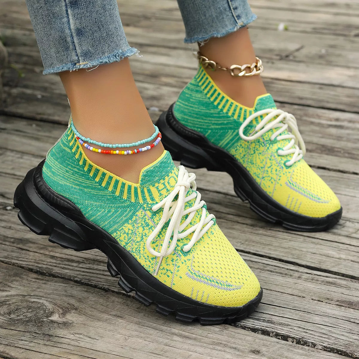 Bright yellow and green knit mesh sneakers with white laces, black rubber soles, and a flat sporty design.