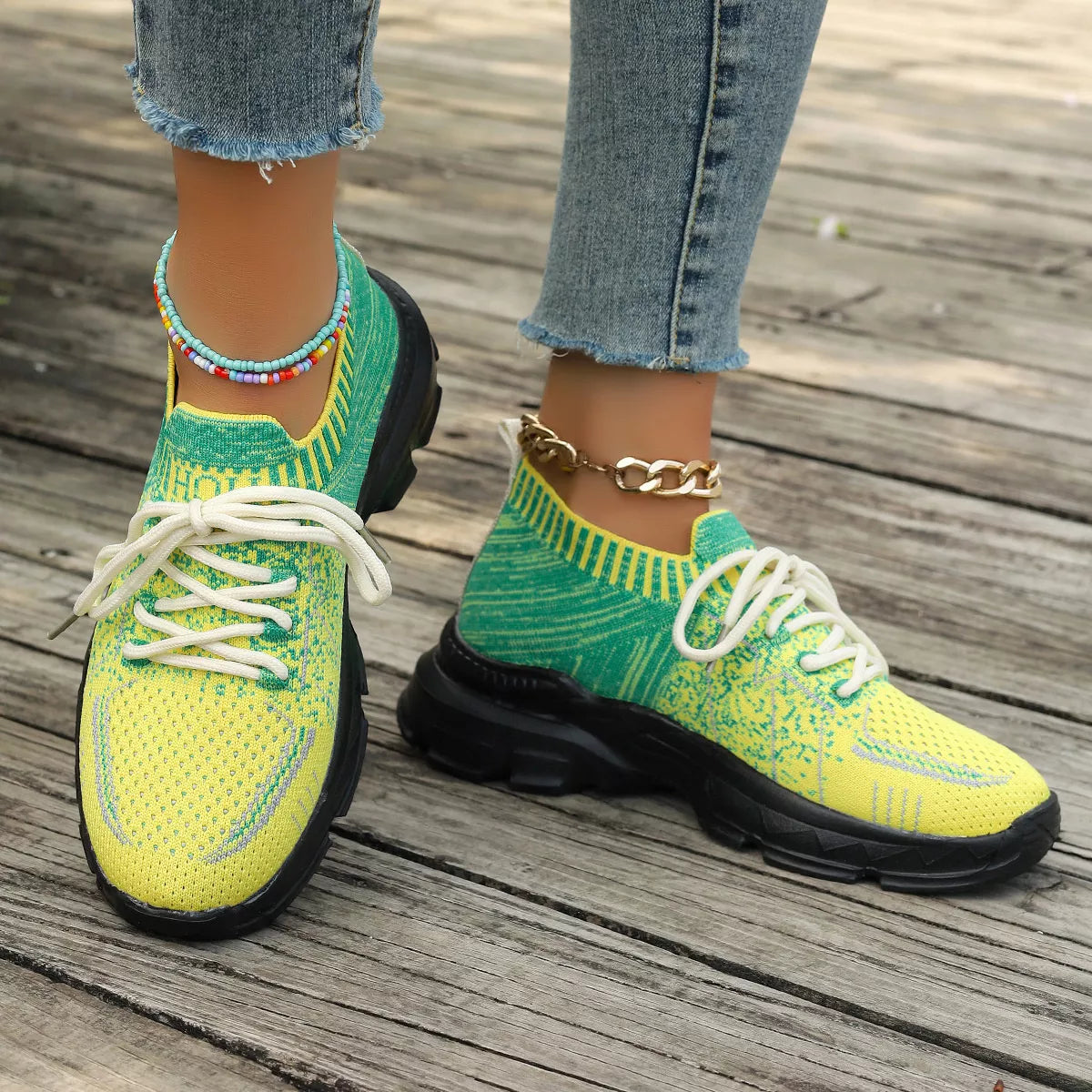 Bright yellow and green knit mesh sneakers with white laces, black rubber soles, and a flat sporty design.
