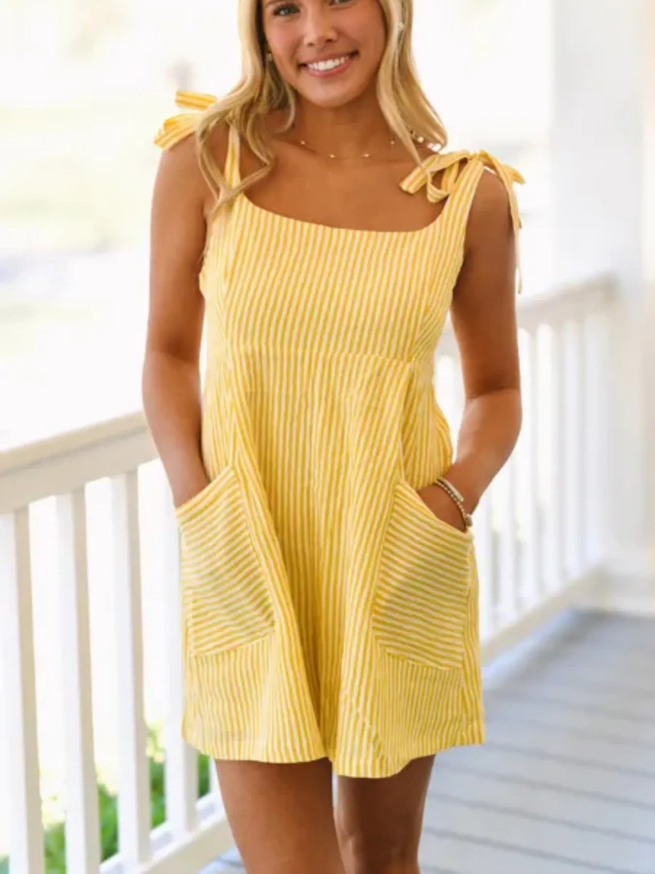 Yellow striped smocked romper with tie shoulder straps and front pockets