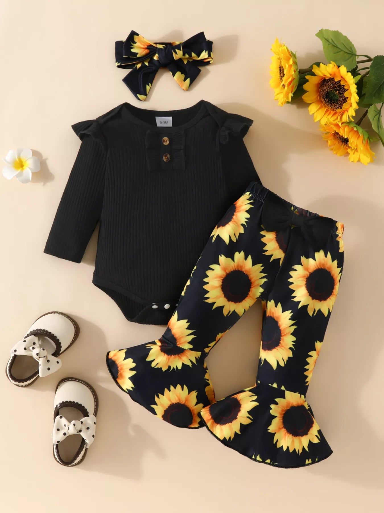 Baby outfit featuring a black ruffled romper, sunflower bell-bottom pants, and matching sunflower bow headband styled with floral decor.