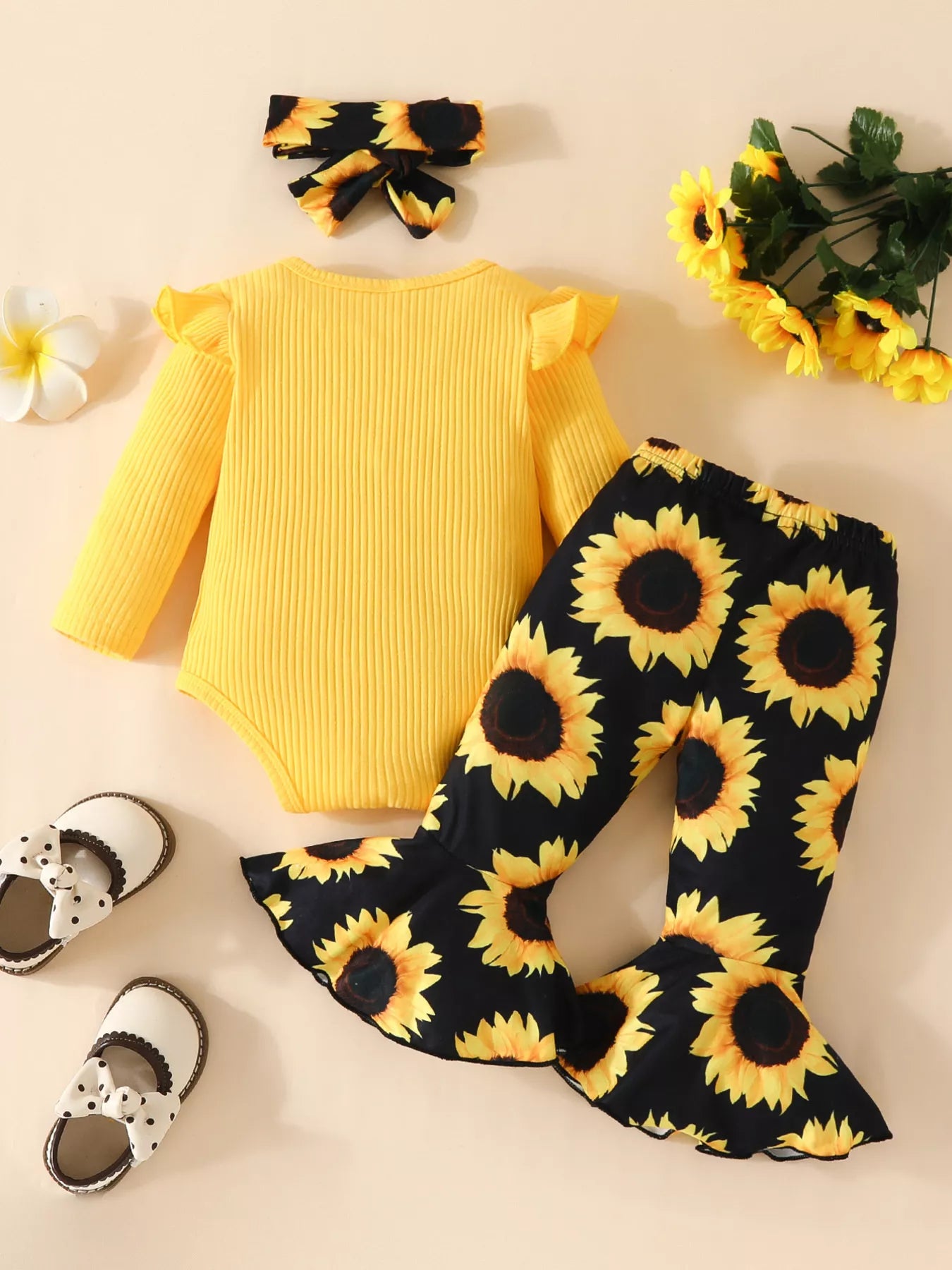 Baby outfit featuring a yellow ruffled romper, sunflower bell-bottom pants, and matching sunflower bow headband displayed flat with floral accents.