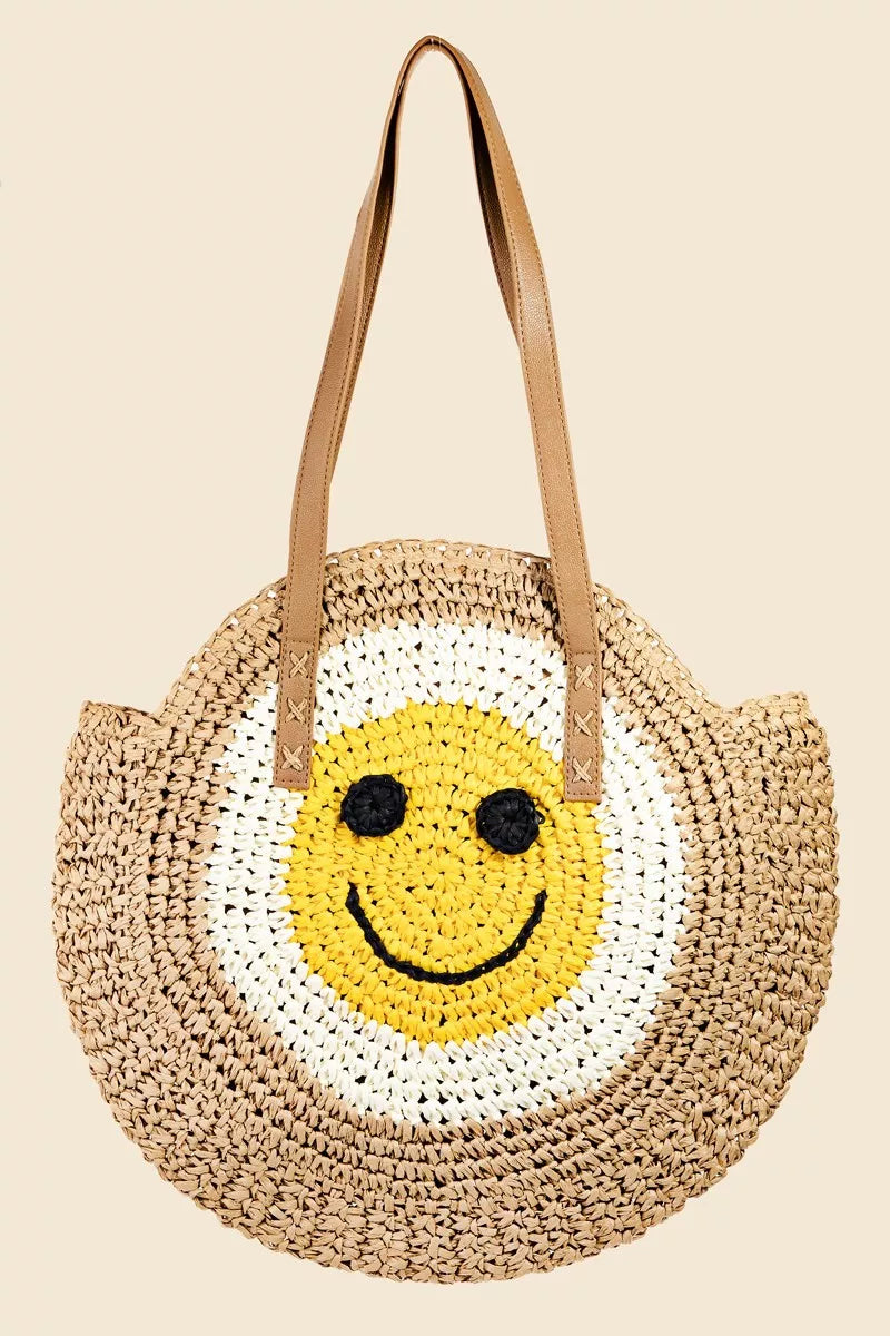 Round straw tote bag with braided design and happy face motif.