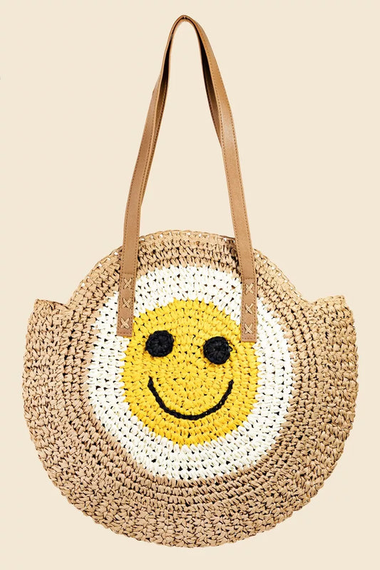 Round straw tote bag with braided design and happy face motif.
