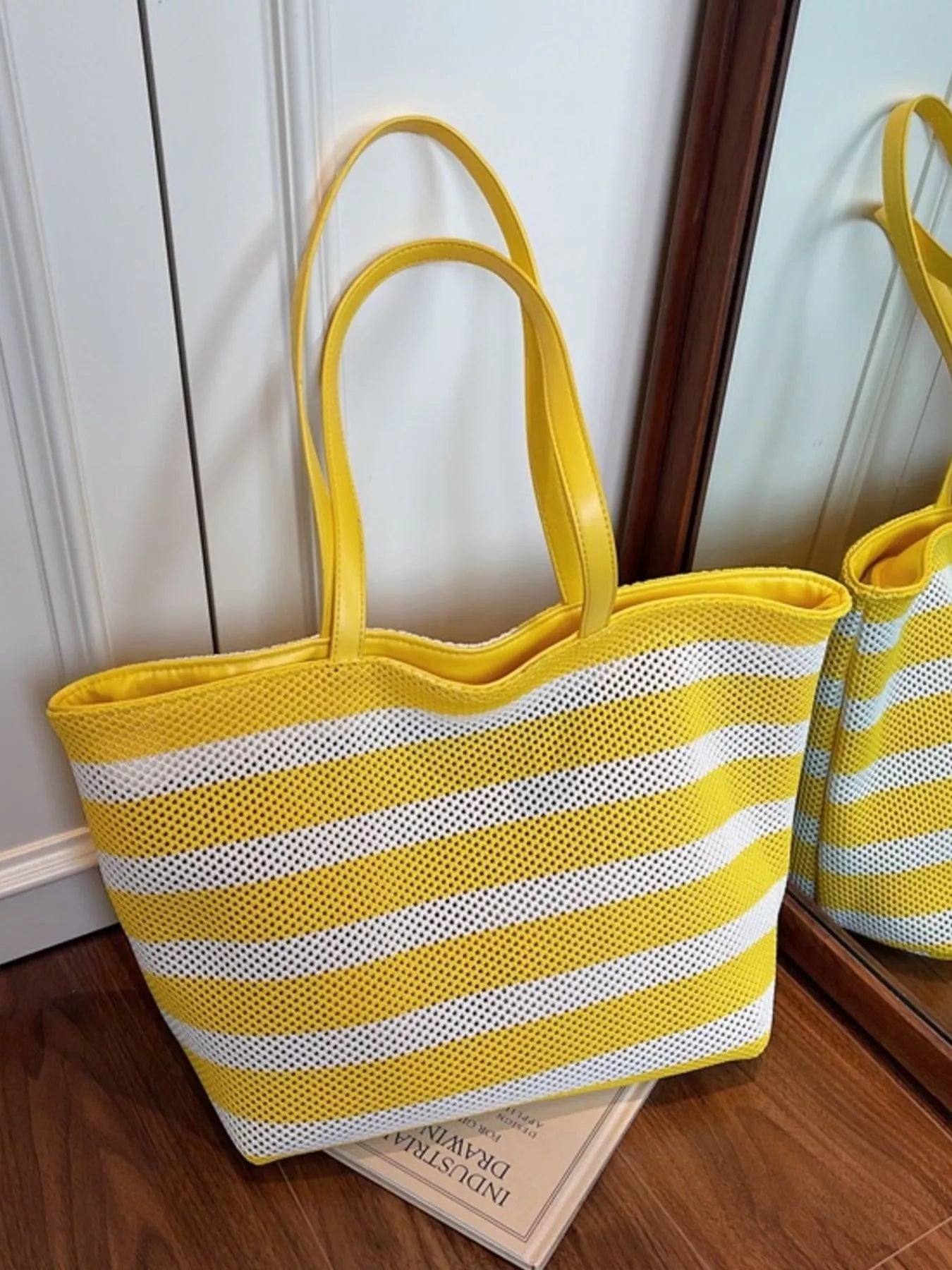 Large yellow and white striped mesh tote bag with shoulder straps, lightweight polyester material, and casual everyday styling.