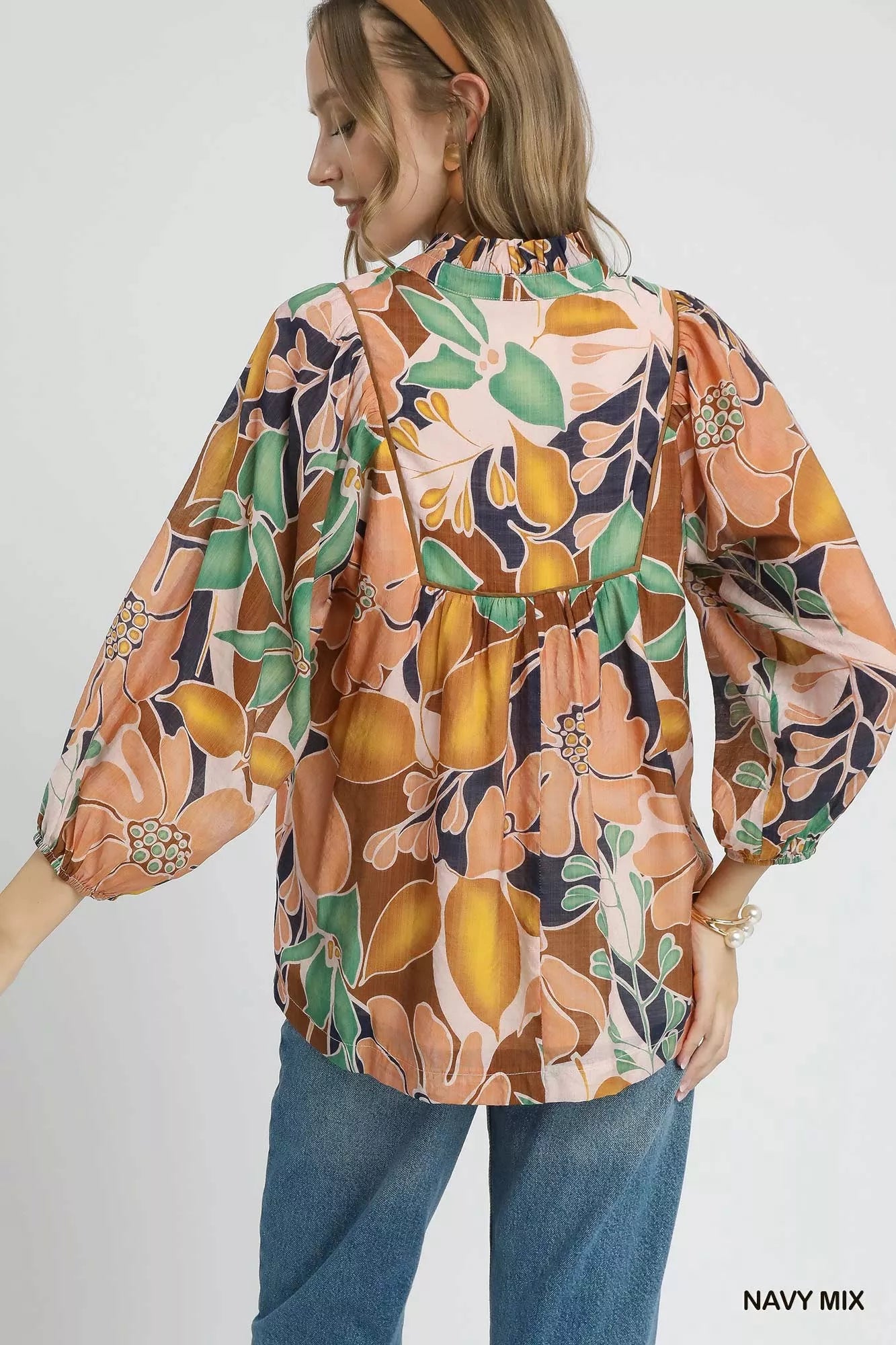 Multicolor abstract floral print blouse with ruffle neck and long sleeves.