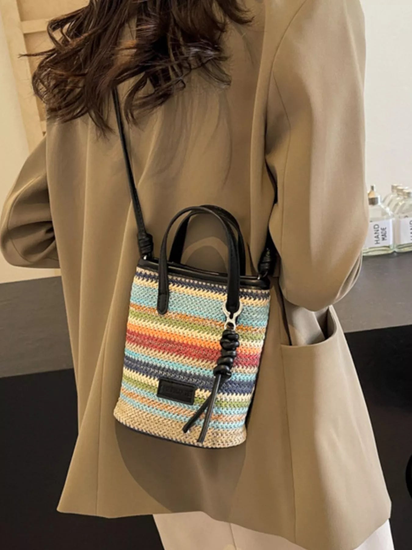small rainbow striped woven straw mini bag with black handles and crossbody strap in a boho style