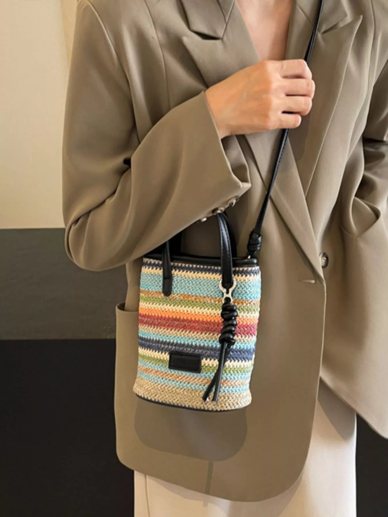 small rainbow striped woven straw mini bag with black handles and crossbody strap in a boho style
