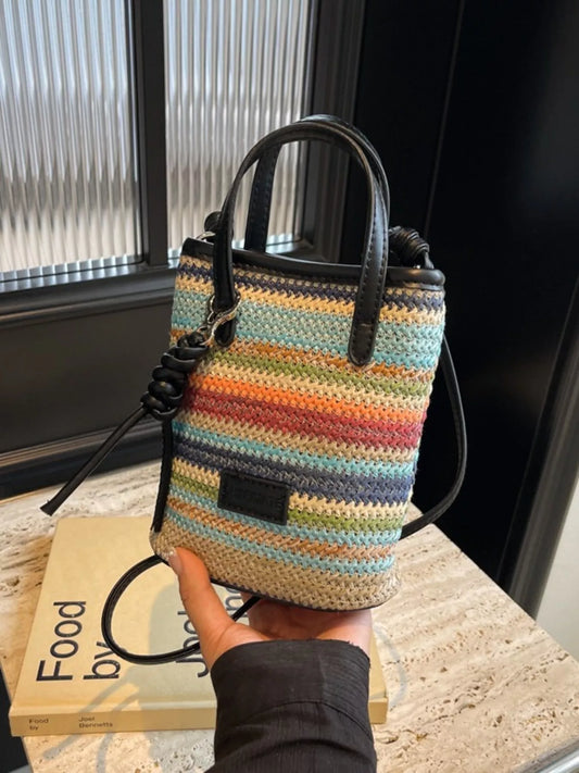 small rainbow striped woven straw mini bag with black handles and crossbody strap in a boho style