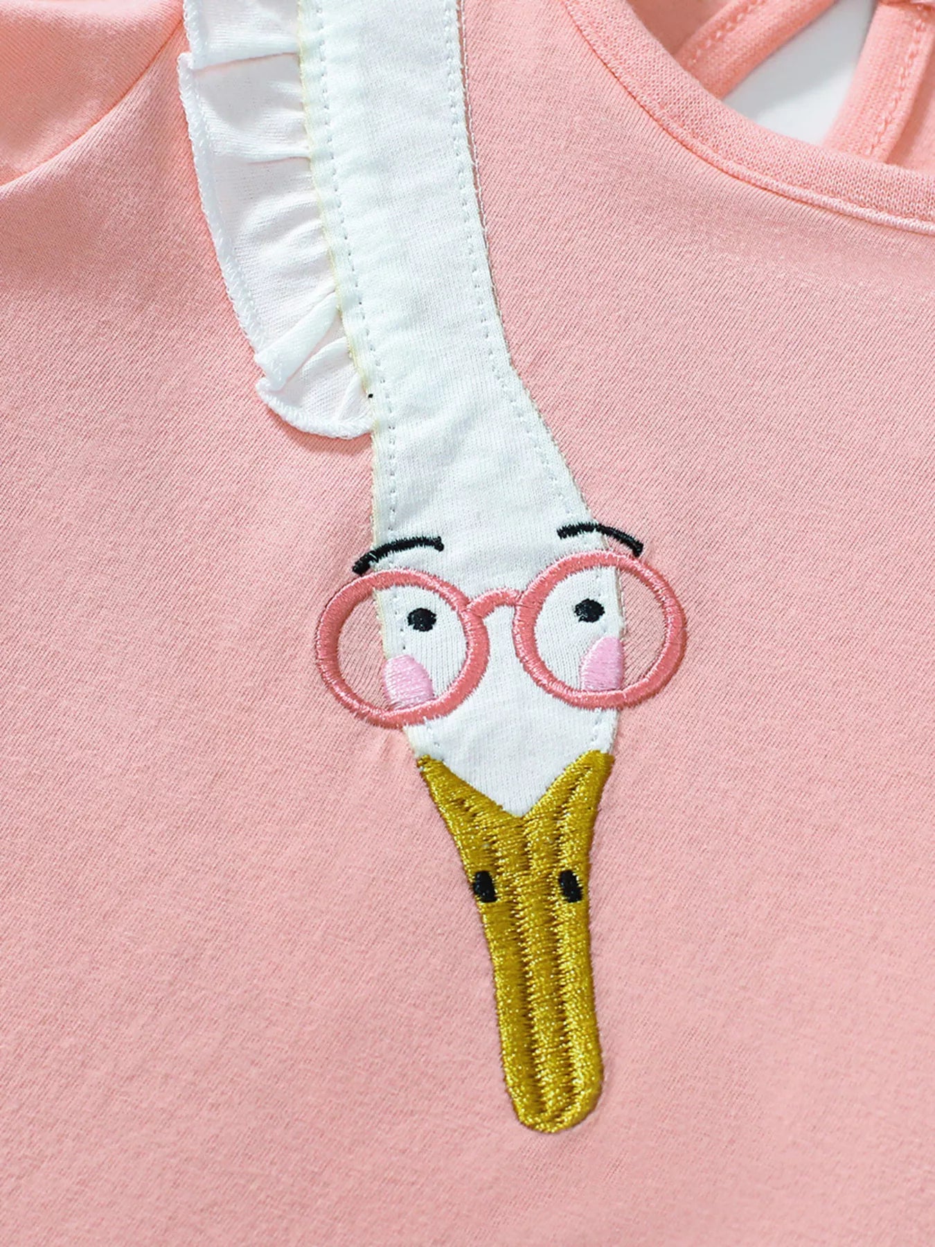 Pink girls dress with flutter sleeves and playful bird detail styled indoors