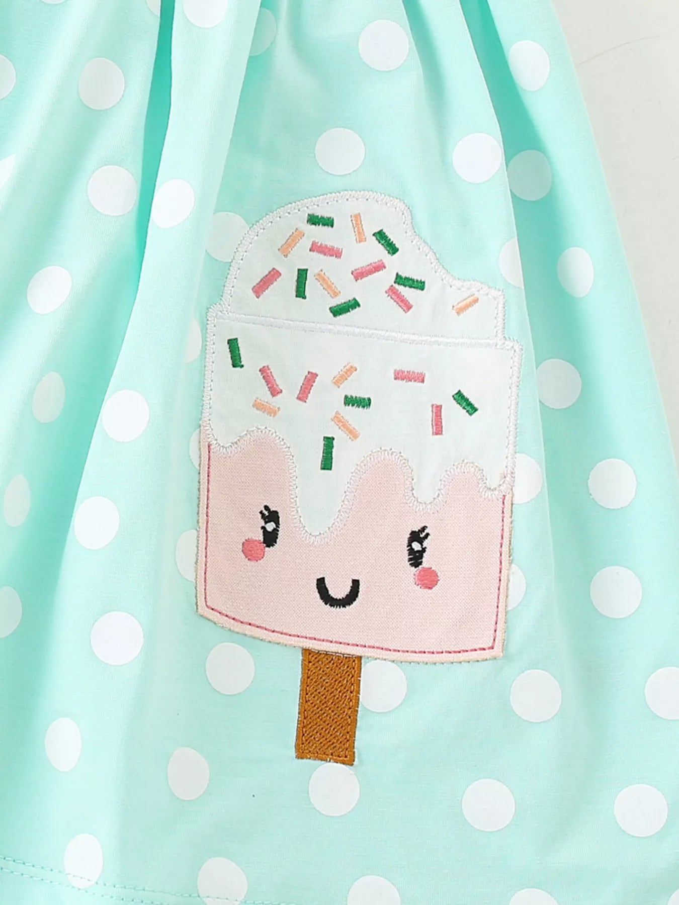 Toddler wearing mint green polka dot dress with popsicle pocket detail