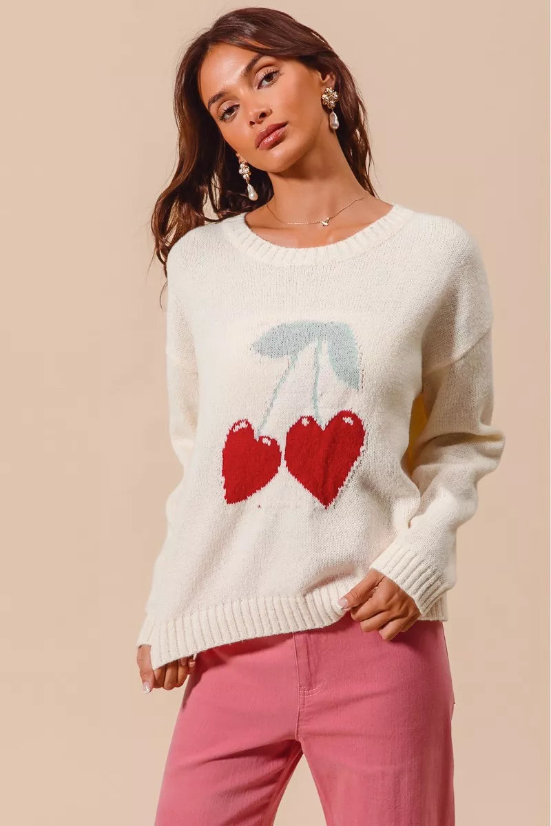 Cream knit sweater with red heart-shaped cherry design on model