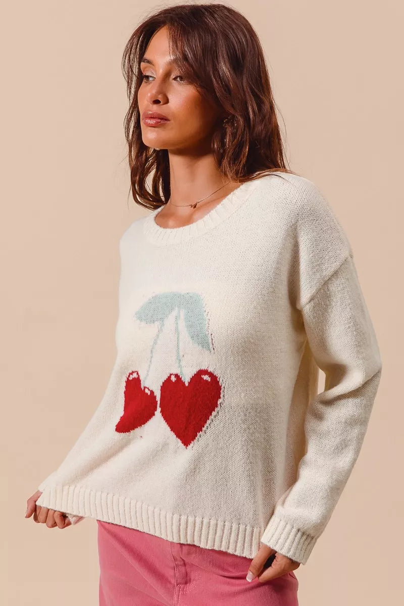 Cream knit sweater with red heart-shaped cherry design on model