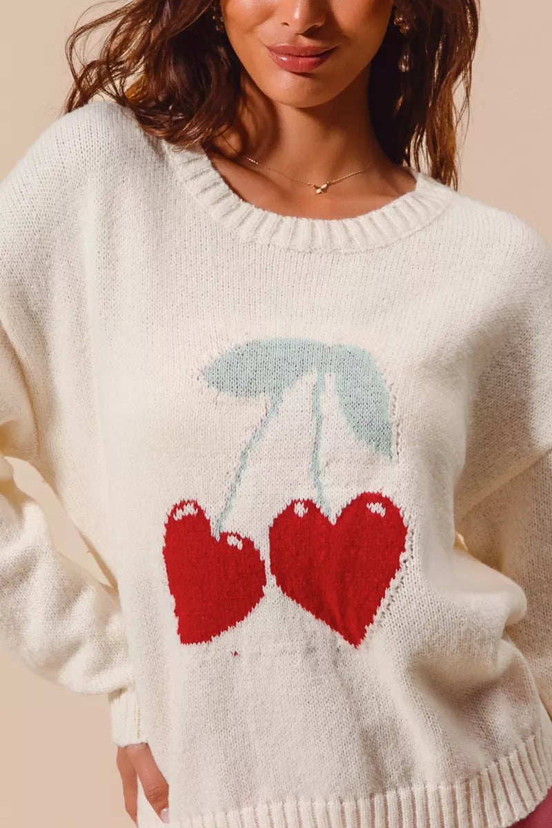 Cream knit sweater with red heart-shaped cherry design on model