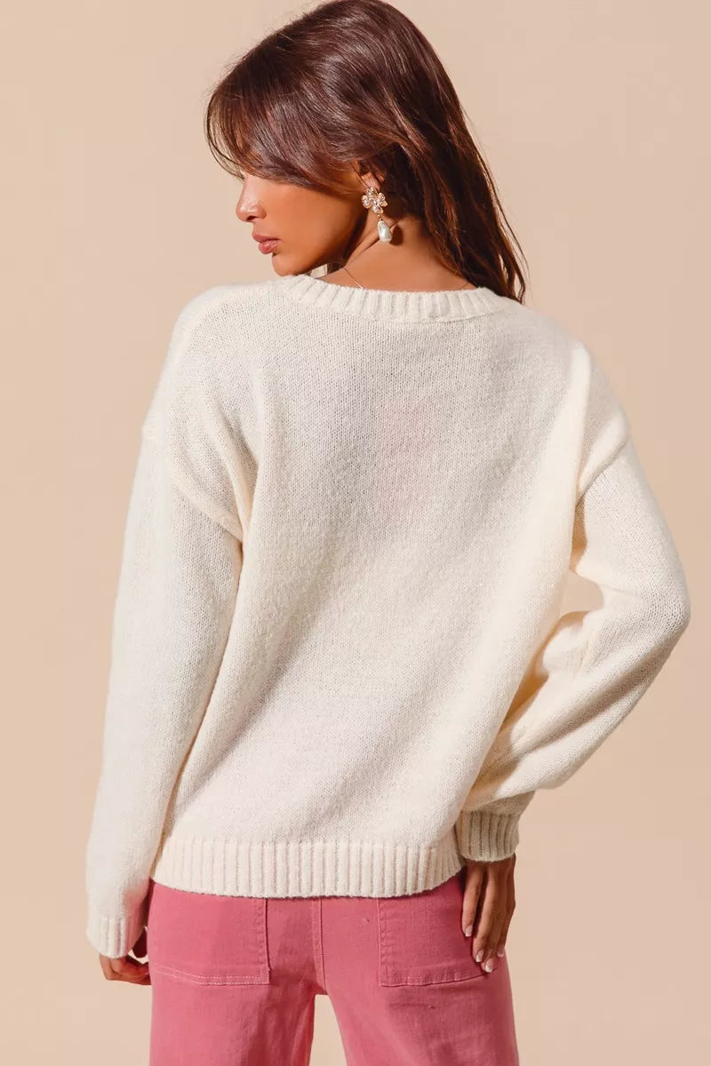 Cream knit sweater with red heart-shaped cherry design on model