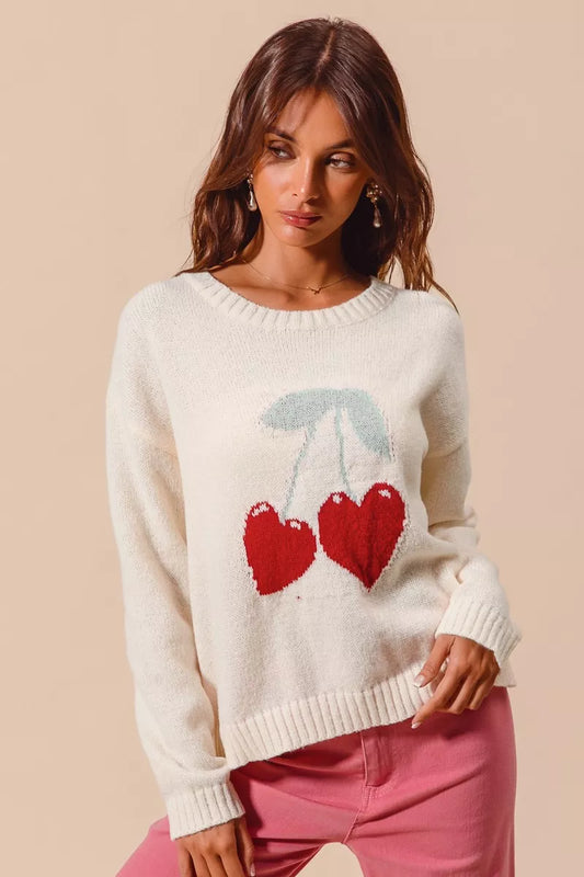 Cream knit sweater with red heart-shaped cherry design on model