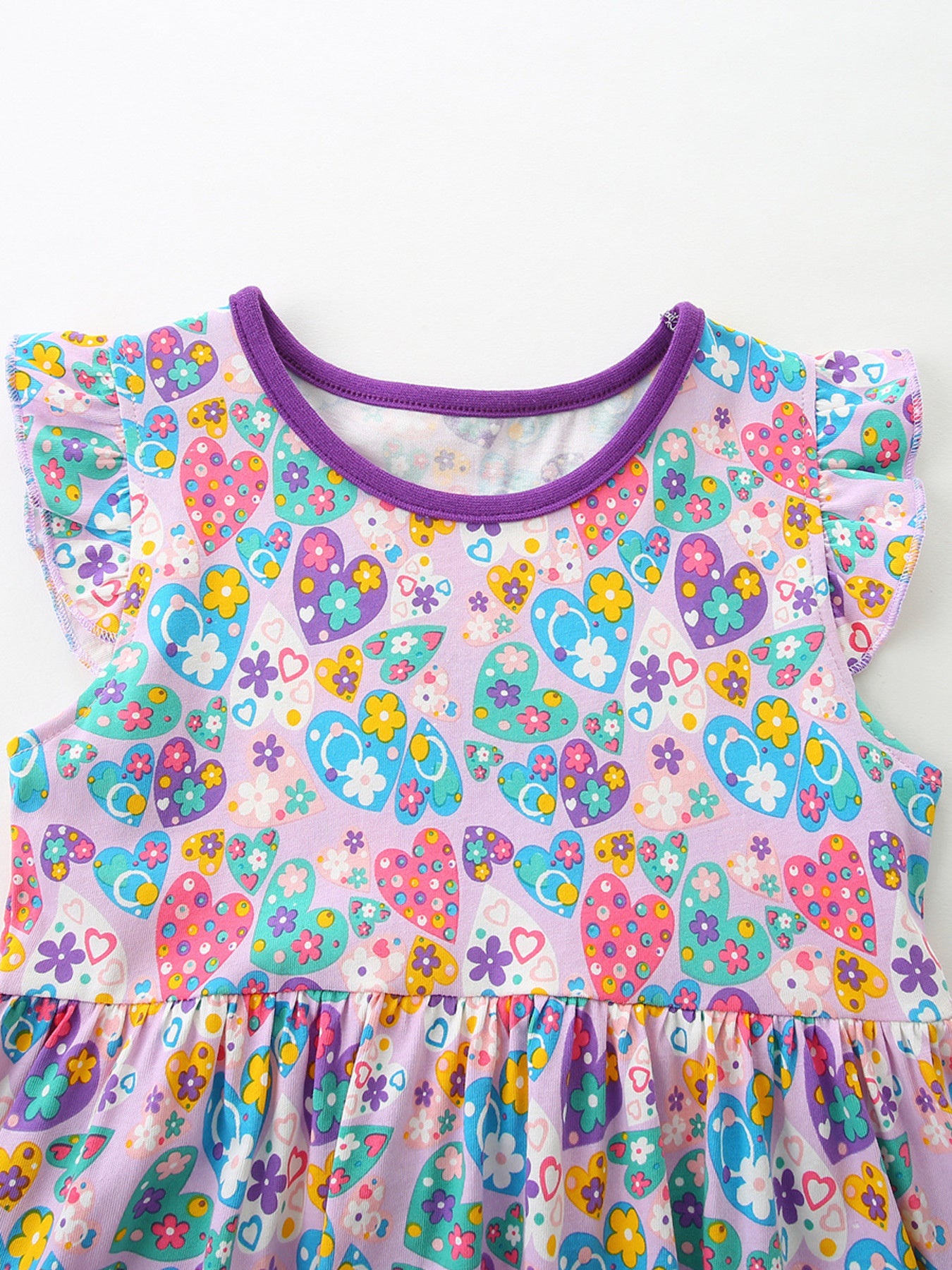 Girls cotton dress with colorful paisley floral print, purple trim, flutter sleeves, and heart-shaped front pockets.