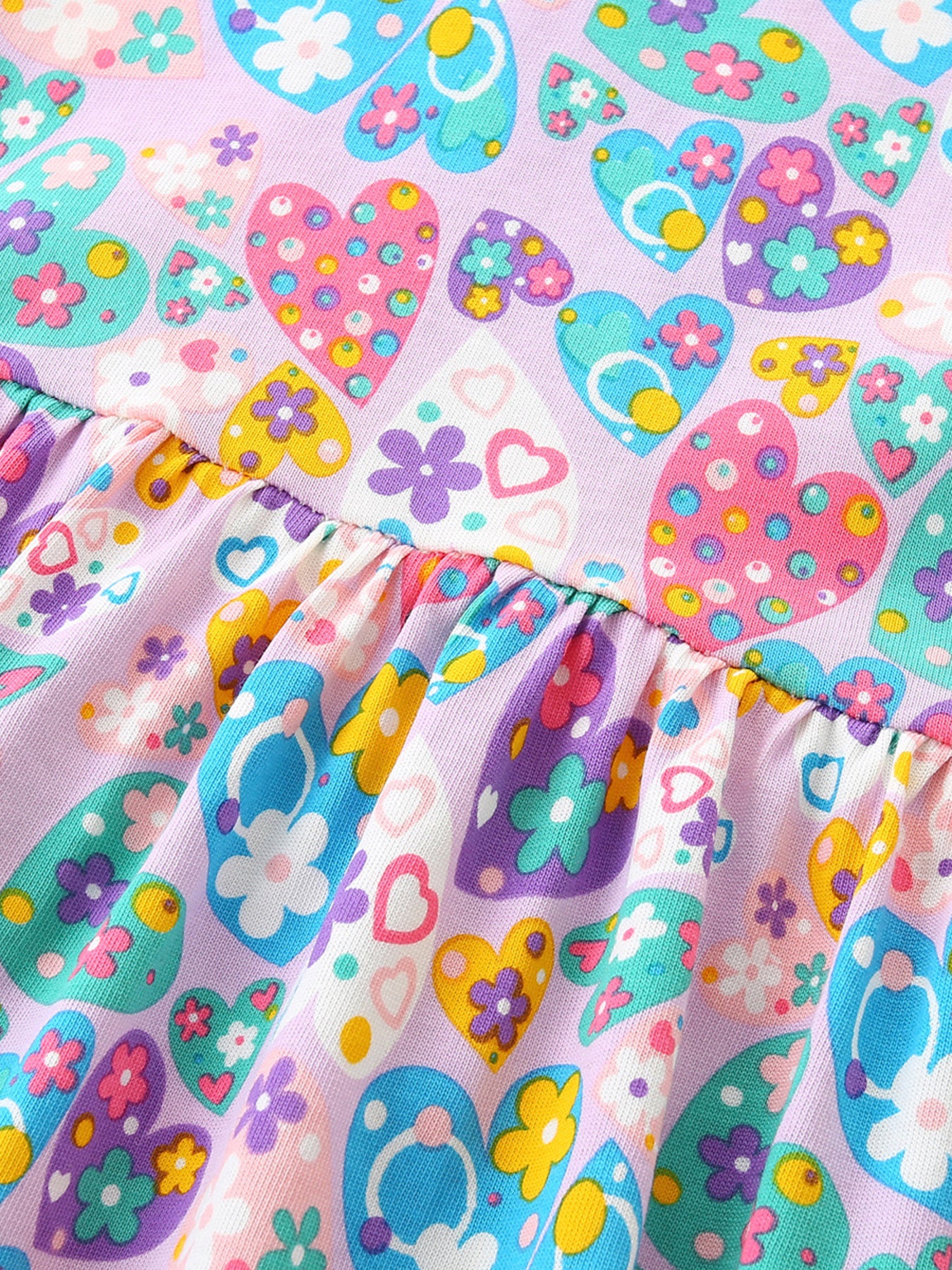 Girls cotton dress with colorful paisley floral print, purple trim, flutter sleeves, and heart-shaped front pockets.
